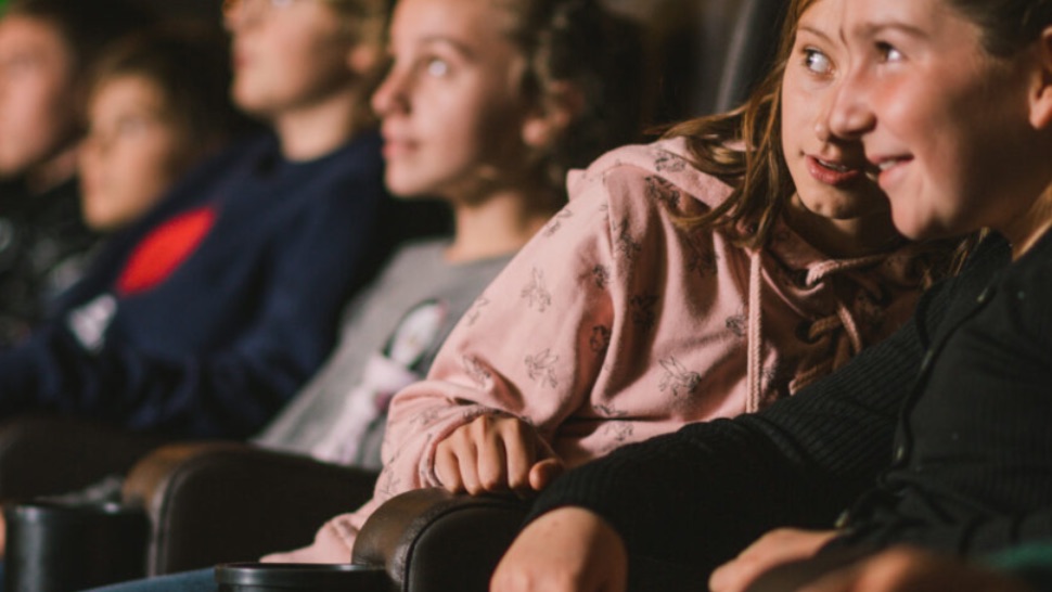Kinder sitzen gespannt im Kino.